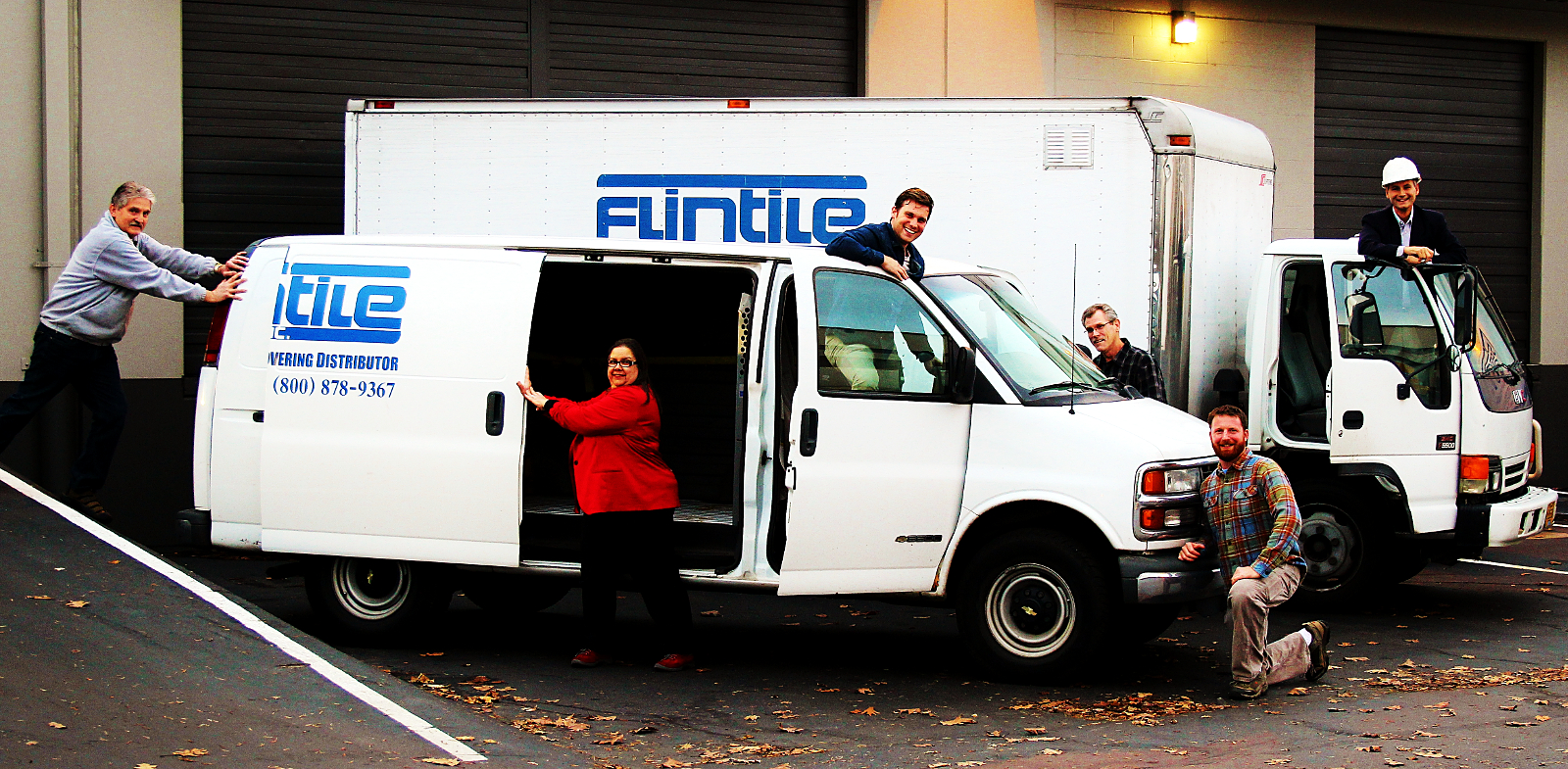 The Flintile Inc team playfully horsing around the work vans